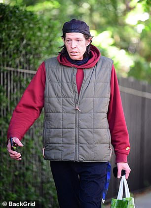 The filmmaker layered up despite the summery weather while wearing a red Nike hoodie over a navy blouse.