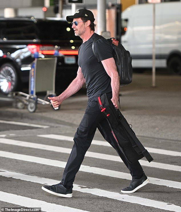 She finished her look with a pair of matching black pants, a baseball cap, dark aviator sunglasses, and a pair of black sneakers with white trim.