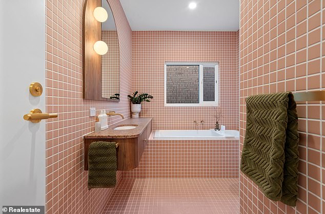 The master bathroom is especially striking with floor-to-ceiling pink tile, a curved shower, and a spacious tub.