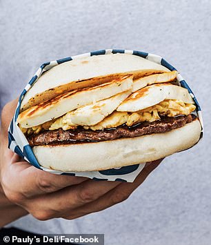 A giant breakfast sandwich with cevapi and scrambled eggs.