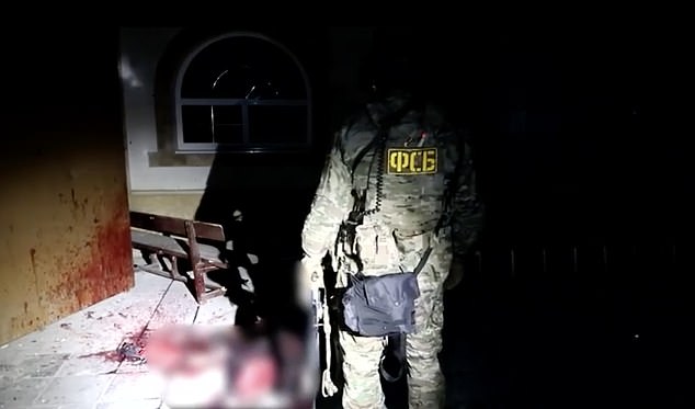 A member of the Russian national security service FSB is seen standing next to a bloody body. It is not clear whether the body is that of a terrorist or a victim.