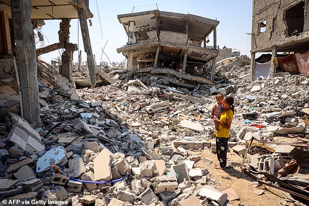 A woman holds a child surrounded by the rubble of buildings destroyed during the Israeli bombardment in Khan Yunis, southern Gaza Strip, June 23, 2024.