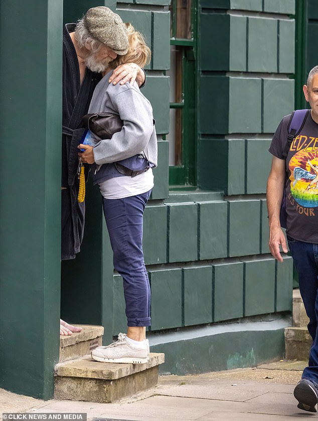 A man walks past as Sir Ian McKellen greets a friend outside his home in London yesterday.