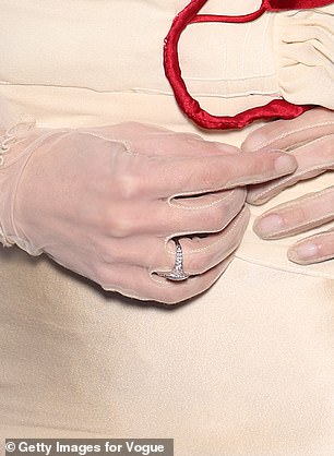 Additionally, she accessorized with a pair of cream-colored sheer gloves and sported a diamond ring after recently sparking engagement rumors (pictured).