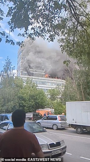 Passersby watch smoke billow from the building.