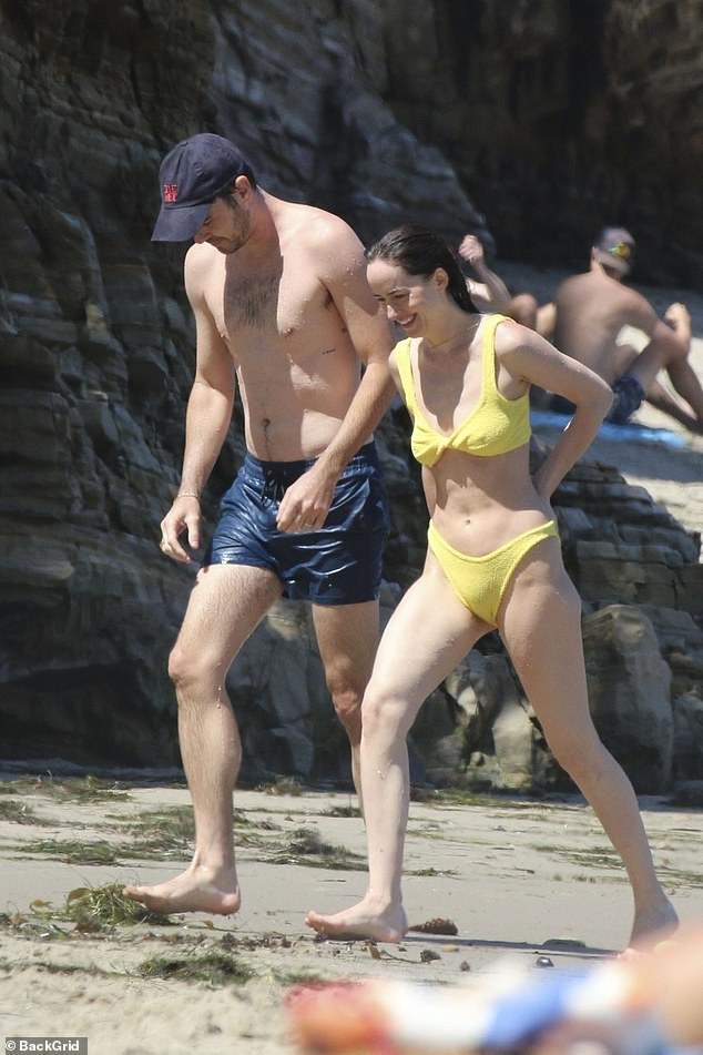 The actress flashed a big smile as she walked across the sand with her friend.