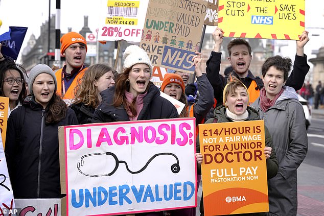 Young doctors hold placards as they picket outside St Thomas' Hospital in Westminster in London, Monday March 13, 2023.