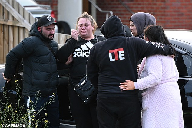 Cory Lewis (left) comforts his older sister Jessica Lewis (second from right) outside the unit in Broadmeadows on Tuesday morning.