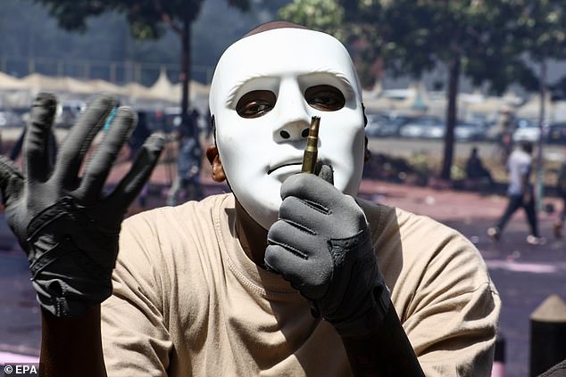 A masked protester holds an empty ammunition magazine used by police during a protest against the proposed tax increase.