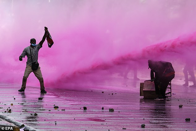 Protesters react as police use a water cannon during a protest against proposed tax increases.