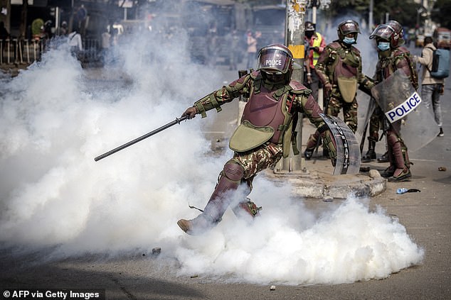 A Kenyan police officer kicks a tear gas canister during a nationwide strike to protest tax increases.