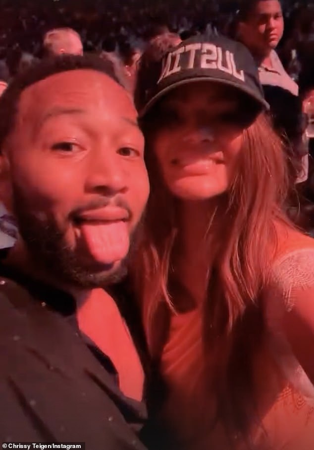 The Cravings founder, 38, wore the hat, which is not part of the troubled 43-year-old pop star's official merchandise, alongside her husband John Legend (left).