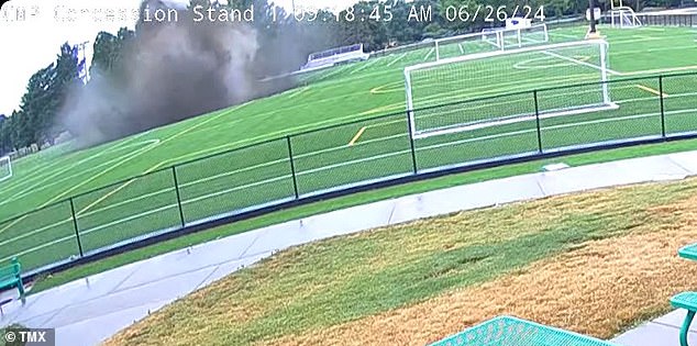 One of the stadium's tall lights sinks into the hole and then disappears completely as it is swallowed before a cloud of dust appears.