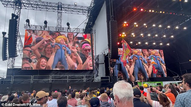 Wearing his striped one-piece pajamas and ear protectors, the little boy was greeted with an enthusiastic reception atop the shoulders of his father, Tom Kay, as special effects on stage made his image become a picture of hallucinatory dance