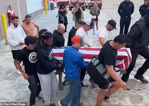 The young man's body was seen with an American flag draped over it as local police and fire personnel transported it to the medical examiner's van.