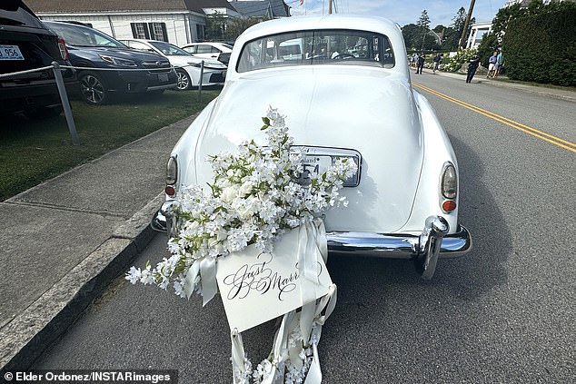 In the back of the car there is a bouquet of flowers and a newlywed card.