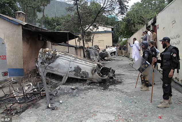 Armed police examine vehicles burned by Muslim mob in last night's attack