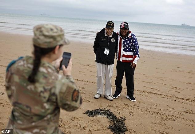 A U.S. soldier takes a photo of American World War II veteran Sid Edson, center left, during a ceremony on Omaha Beach.