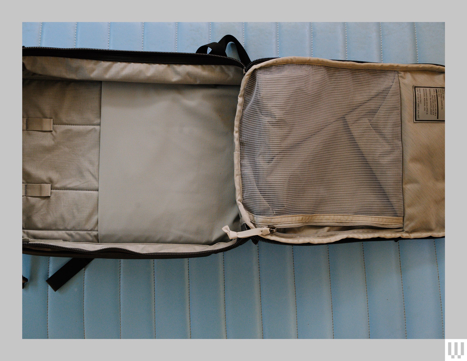 A completely open backpack in a horizontal position with the main flap open showing the entire compartment and the beige interior.