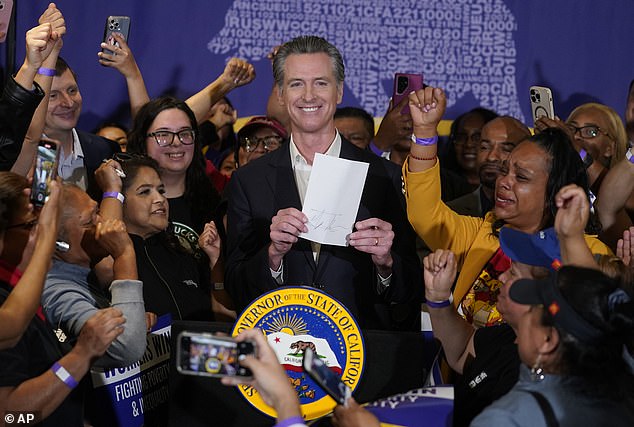 California Governor Gavin Newsom signs the fast food bill raising the minimum wage surrounded by workers at SEIU Local 721 in Los Angeles on September 28, 2023.