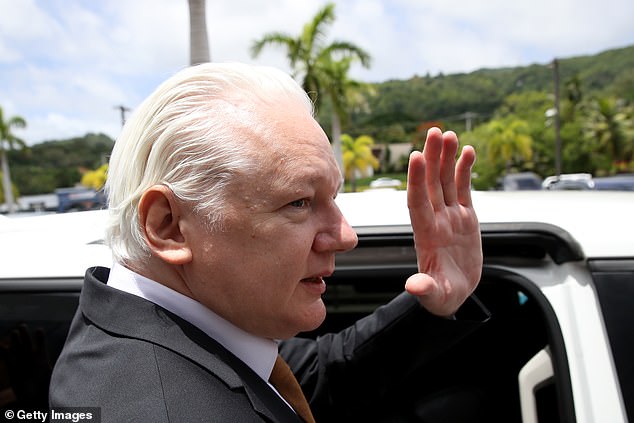 Assange greets the many supporters who cheered him after he left the court.