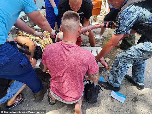 People gather around a Russian tourist who was injured by the Ukrainian missile shot down in Crimea on Sunday.