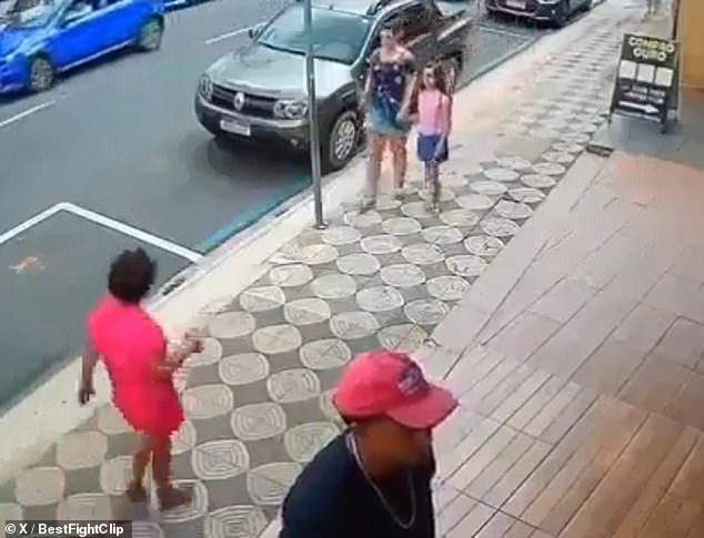 A woman (left) was seen approaching a family on a Brazilian sidewalk before punching a child in the face.