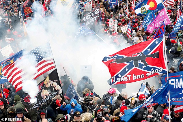 Tear gas is fired into a crowd of protesters, one of them wielding a Confederate battle flag that reads 