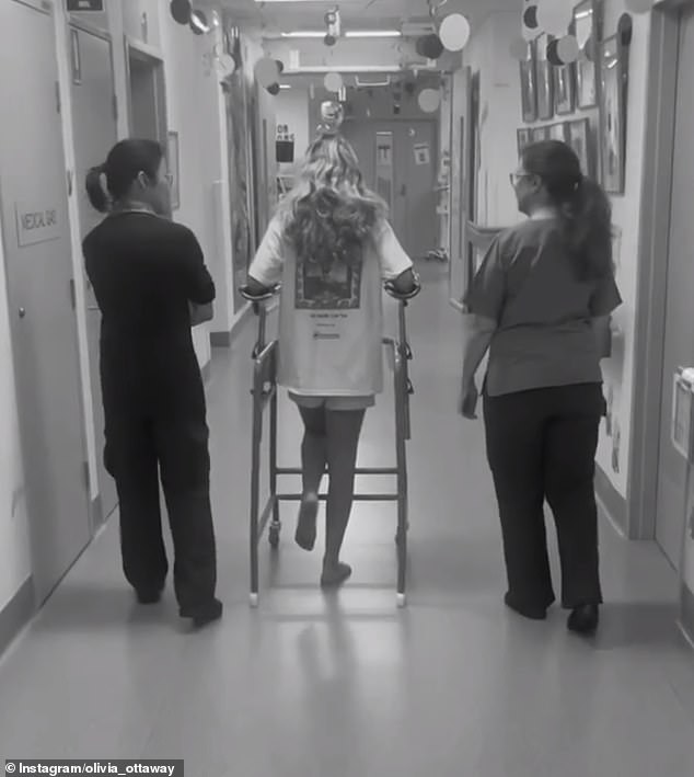 The photo shows Olivia beginning the process of learning to walk again using a frame while in the hospital.