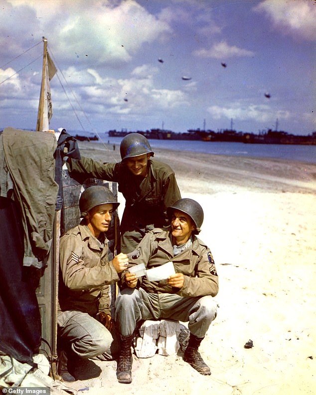 US soldiers Sergeant RA Forbis, Private John Krisa and Corporal VE Holtz of the Army Corps of Engineers read letters on an unidentified beach captured on D-Day.