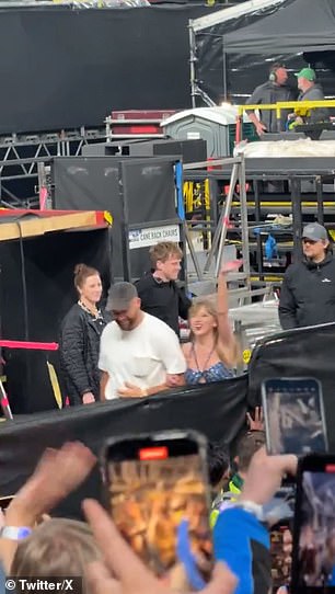 Taylor waves to the crowd as she and Travis walk arm in arm off stage in Dublin.