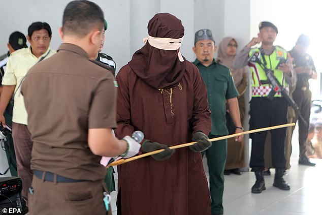 Footage showed an intimidating enforcer, known as an 'algojo', grabbing a rattan before carrying out the public flogging of four men in front of Islamic court officials.