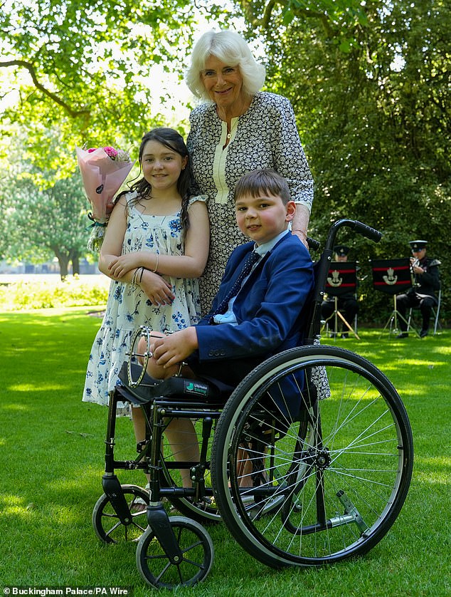 Queen Camilla with Tony Hudgell, from West Malling in Kent, and Lyla O'Donovan, from Catterick, during a private tea party in the gardens of Buckingham Palace on Wednesday.