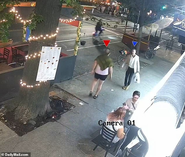 Kaye, 52, continues walking down the sidewalk where she meets another member of the group (red arrow) and the two exchange words.