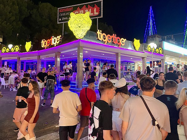 Pictured: Crowds of people gather on the streets of Magaluf following the shocking incidents