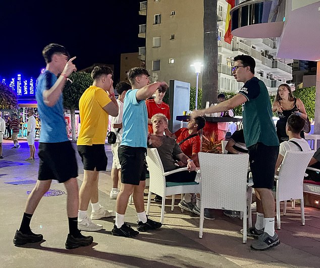 Pictured: A trio of men approach a man holding a tray of drinks as they party the night away.