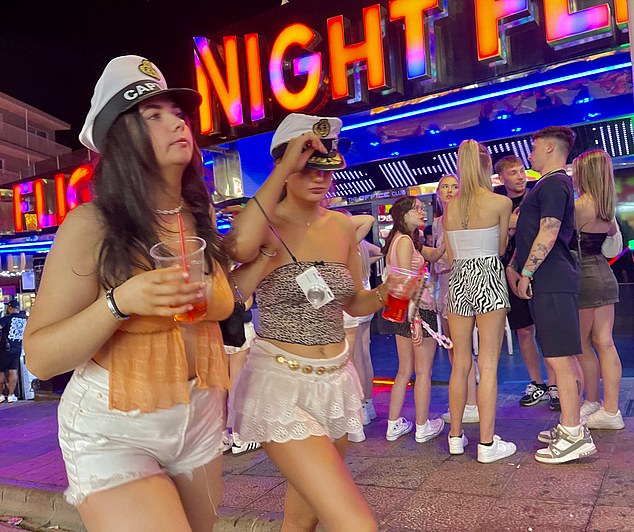 In the picture: Two women wearing party hats with the word 