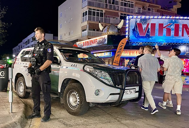 Pictured: Police patrol the area as party-goers wander around behind them.