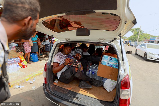 A Jamaican man climbs into the back of a taxi packed with supplies such as water and perishable goods as people prepare for Hurricane Beryl in Kingston.