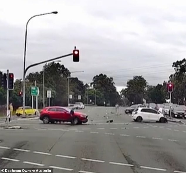 The driver collides with a white Toyota hatchback, which spins 360 degrees before crashing into a red Mazda SUV in the adjacent lane (pictured)