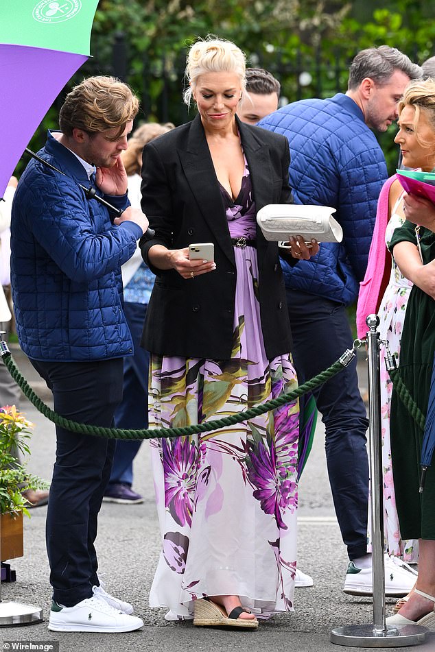 Hannah accessorized her look with statement white sunglasses and sandals and then added a blazer over her summer dress as it started to rain.