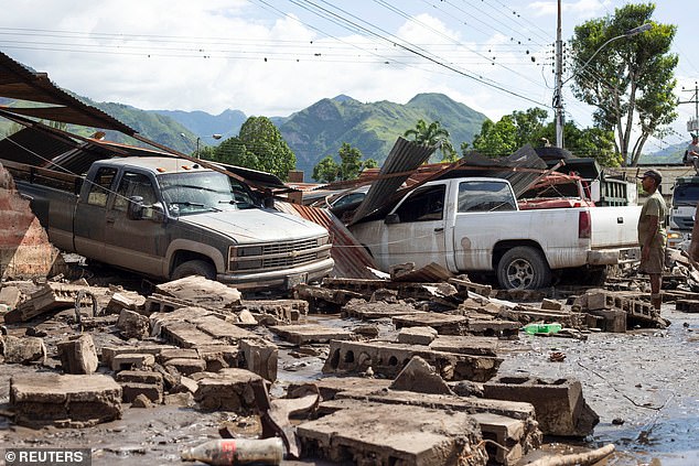 A man looks at damaged vehicles after devastating floods swept through the city following the passage of Hurricane Beryl along the Venezuelan coast, in Cumanacoa, Venezuela, on July 2, 2024.