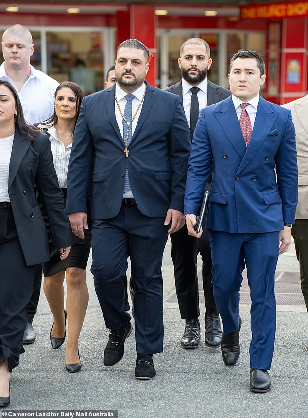 Robbie Awad (center) arrives at the courthouse with an entourage of supporters, including celebrity defense attorney Bryan Wrench. Awad wore a rosary around his neck