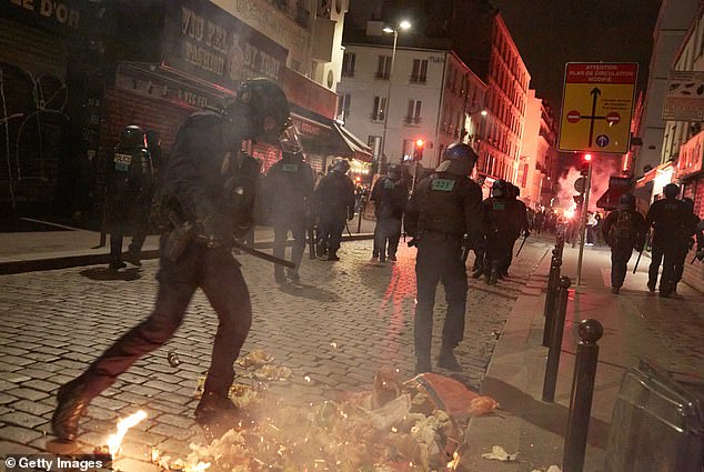 Riot police officers repel protesters who had set fire to piles of rubbish