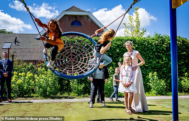 With her hair combed back into a bun, the Dutch monarch watched as children played on playground equipment.