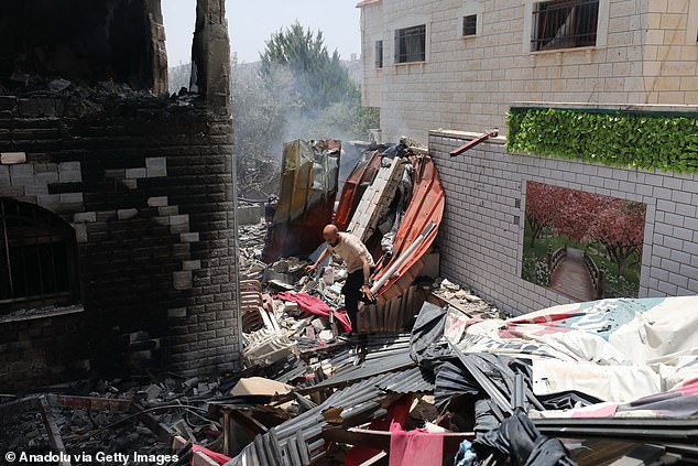 A Palestinian is seen searching through the smoldering rubble of a building that was destroyed by an Israeli strike on Friday.