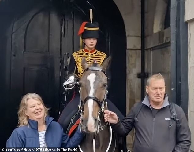 The proud parents then posed with their daughter at their guard post before throngs of tourists descended once again to pose in the rain stroking the horse.