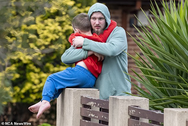 Neighbor Jarrod Hawkins (pictured hugging his son) was praised for running into the burning house. Police said Hawkins' actions 