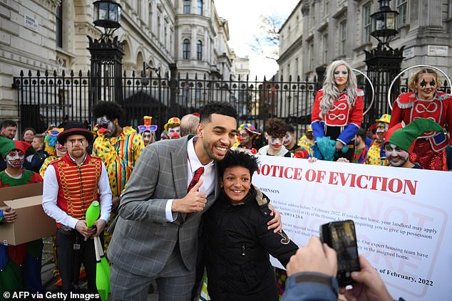 Niko Omilana poses for photographs with a fan as they stand among people in costume during a protest outside the gates of Downing Street, London, February 6, 2022.