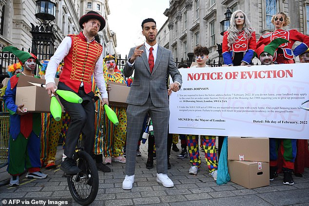 Niko Omilana delivers a speech as he stands among people in costume during a protest outside the gates of Downing Street in London on February 6, 2022.